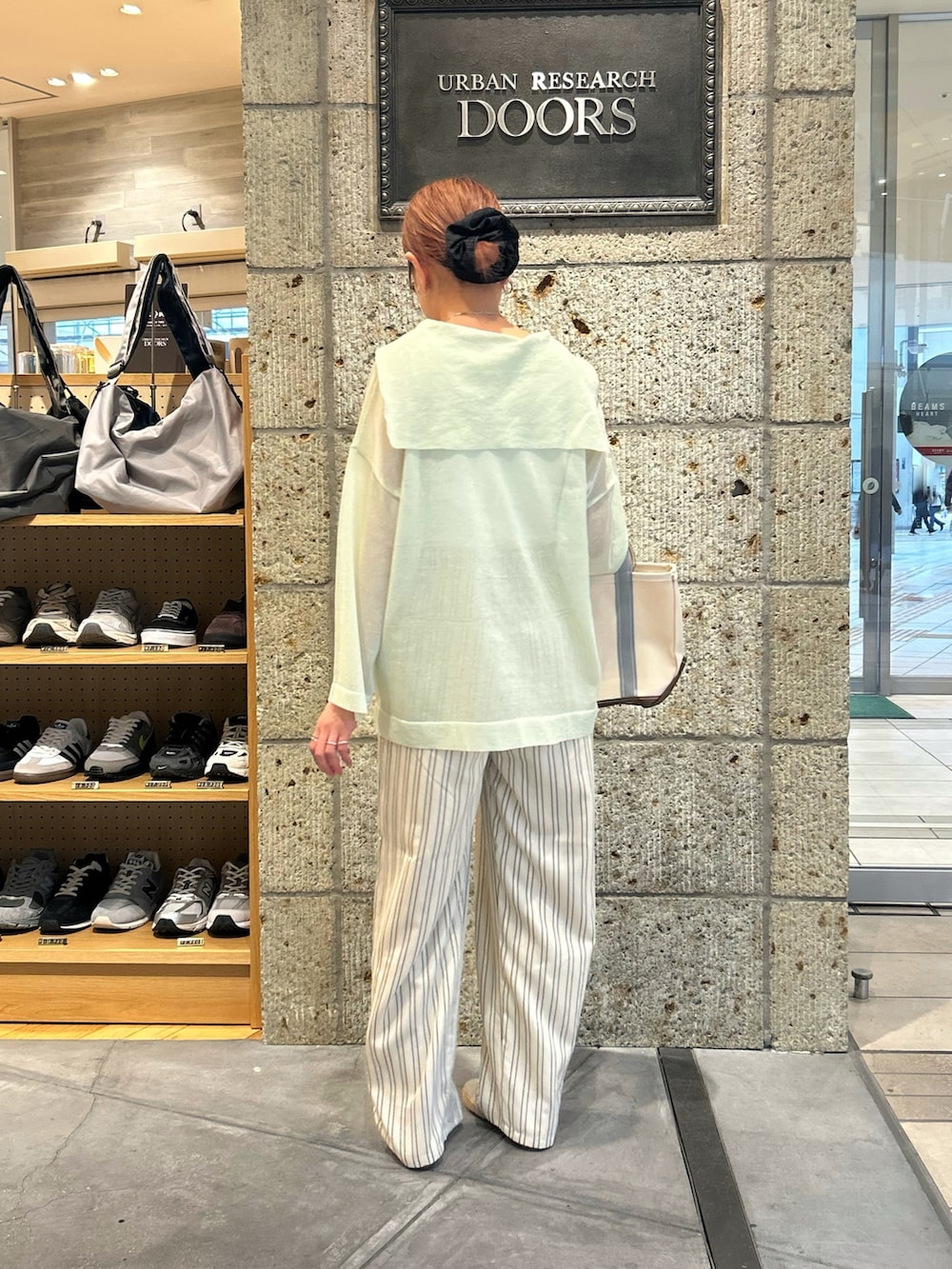 ベージュ系のその他パンツ、シルバー系のスリッポン、グリーン系のトートバッグを着用したレディースの春コーディネートの4枚目の写真