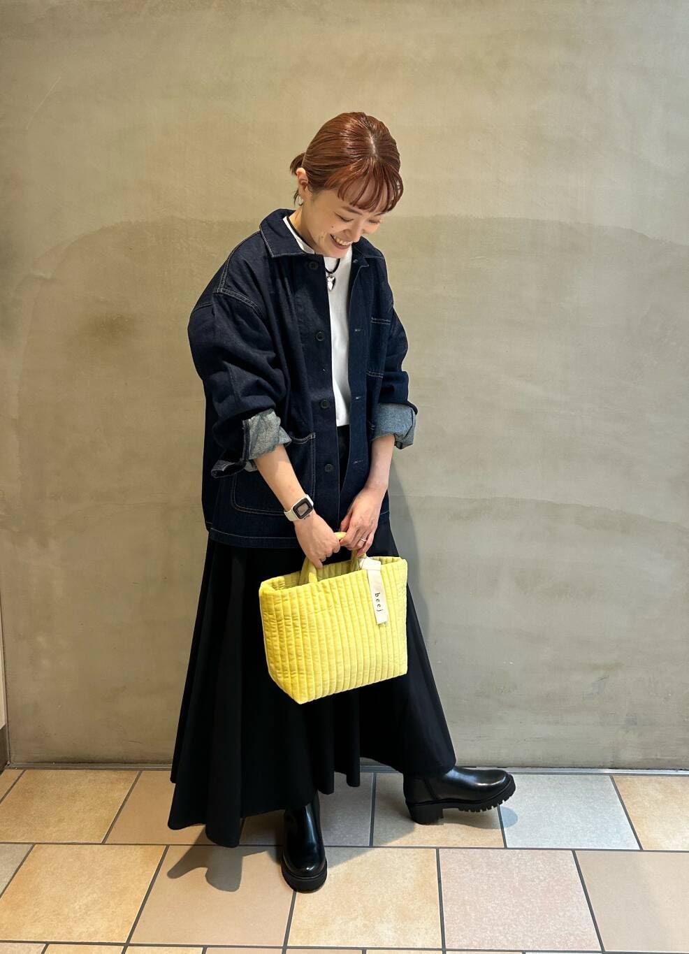 イエロー系のトートバッグ、ホワイト系のTシャツ/カットソー、ブラック系のブーツを着用したレディースの秋コーディネートの2枚目の写真