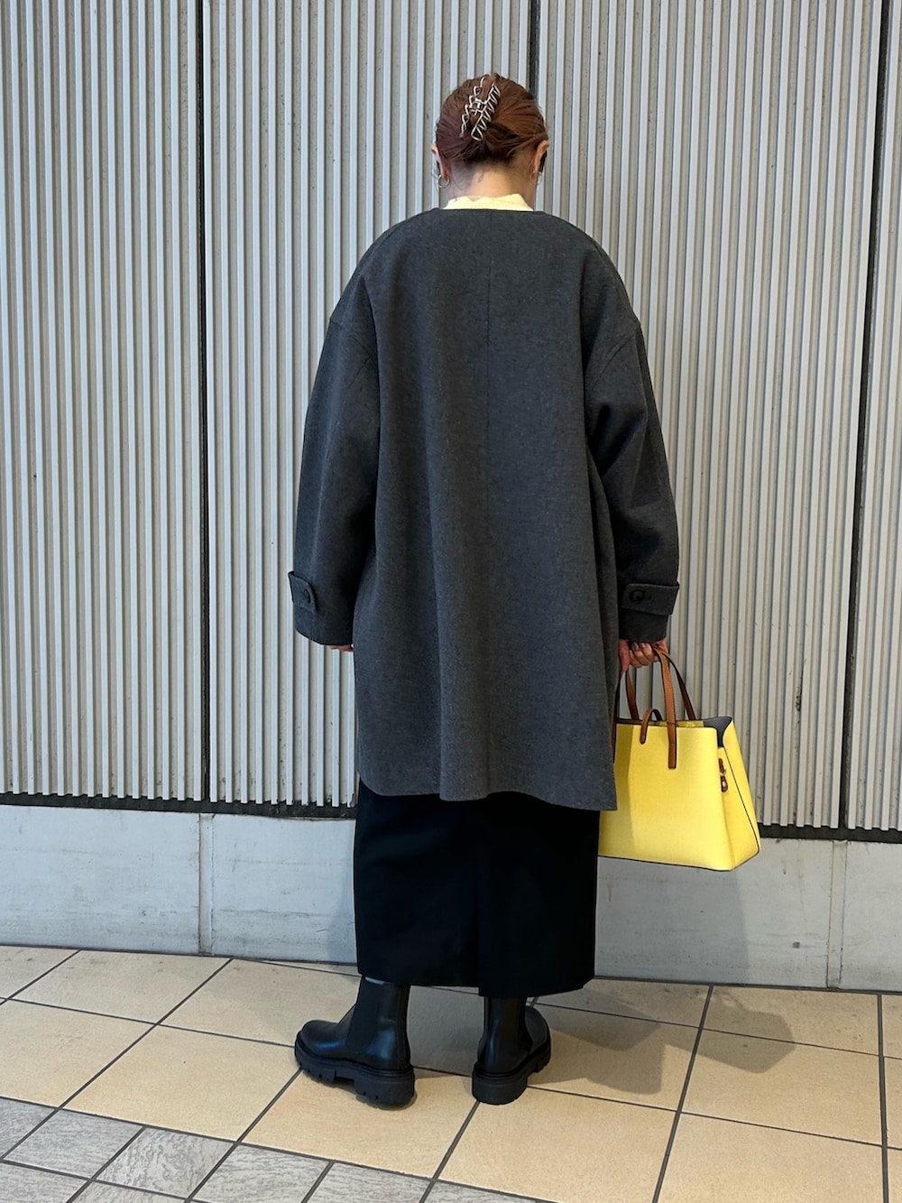 グレー系のその他アウター、イエロー系のニット/セーター、ブラック系のワンピースを着用したレディースの冬コーディネートの2枚目の写真