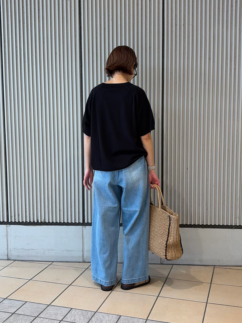 ブラック系のニット/セーター、ブルー系のデニムパンツ、ベージュ系のサンダルを着用したレディースの夏コーディネートの2枚目の写真