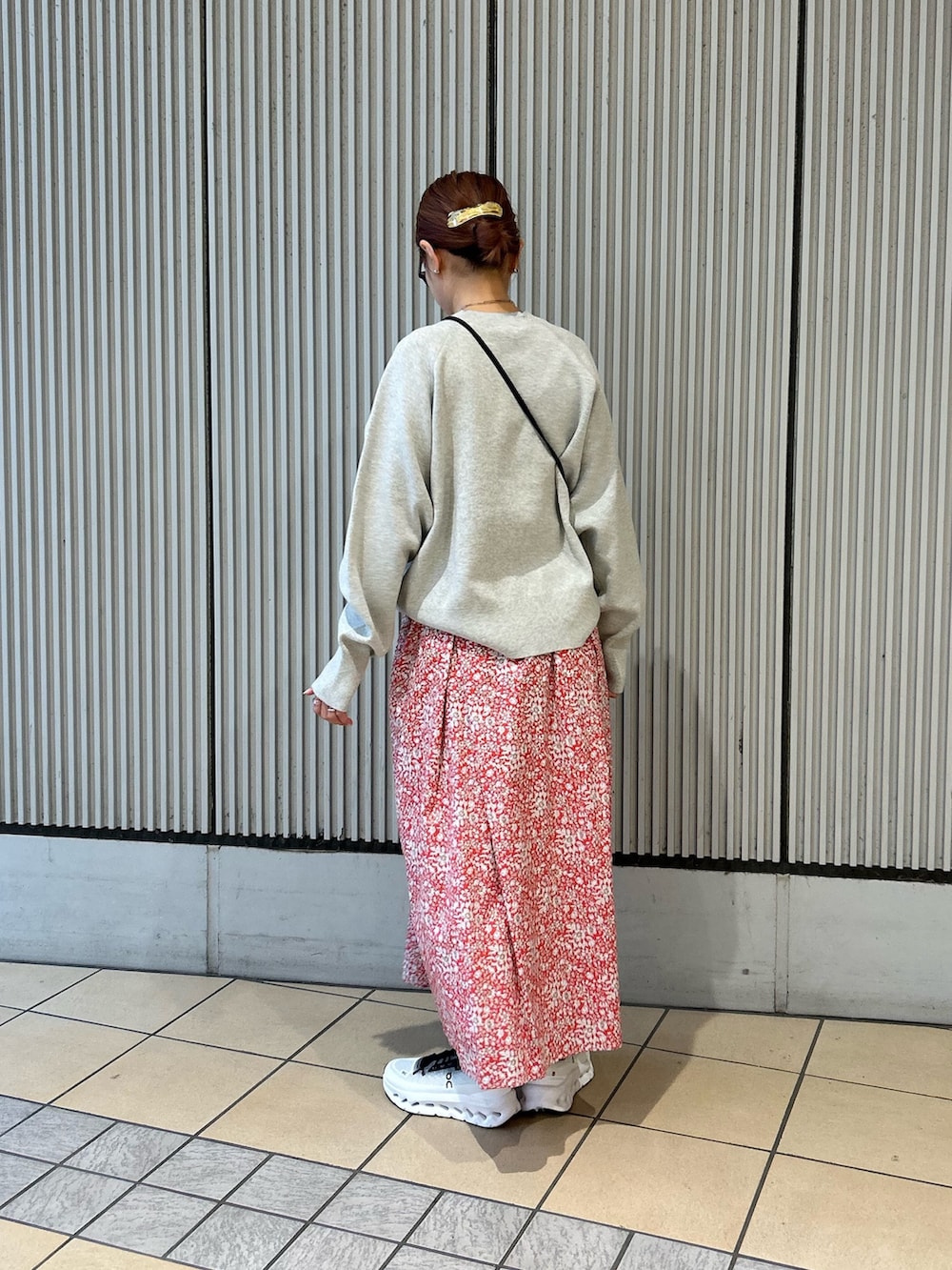 レッド系のスカート、グレー系のニット/セーター、ブラック系のスニーカーを着用したレディースの春コーディネートの3枚目の写真