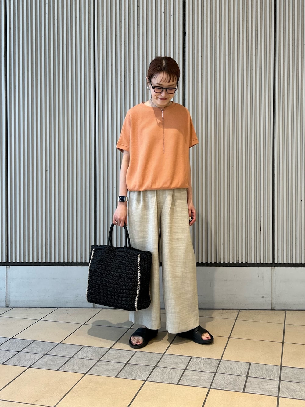 オレンジ系のTシャツ/カットソー、ベージュ系のその他パンツ、ブラック系のトートバッグを着用したレディースの春コーディネートの4枚目の写真