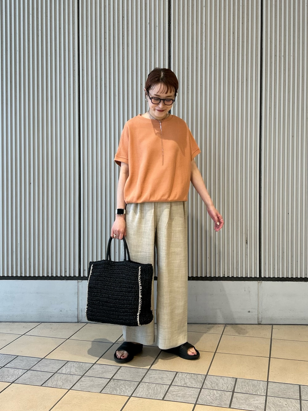 オレンジ系のTシャツ/カットソー、ベージュ系のその他パンツ、ブラック系のトートバッグを着用したレディースの春コーディネートの3枚目の写真