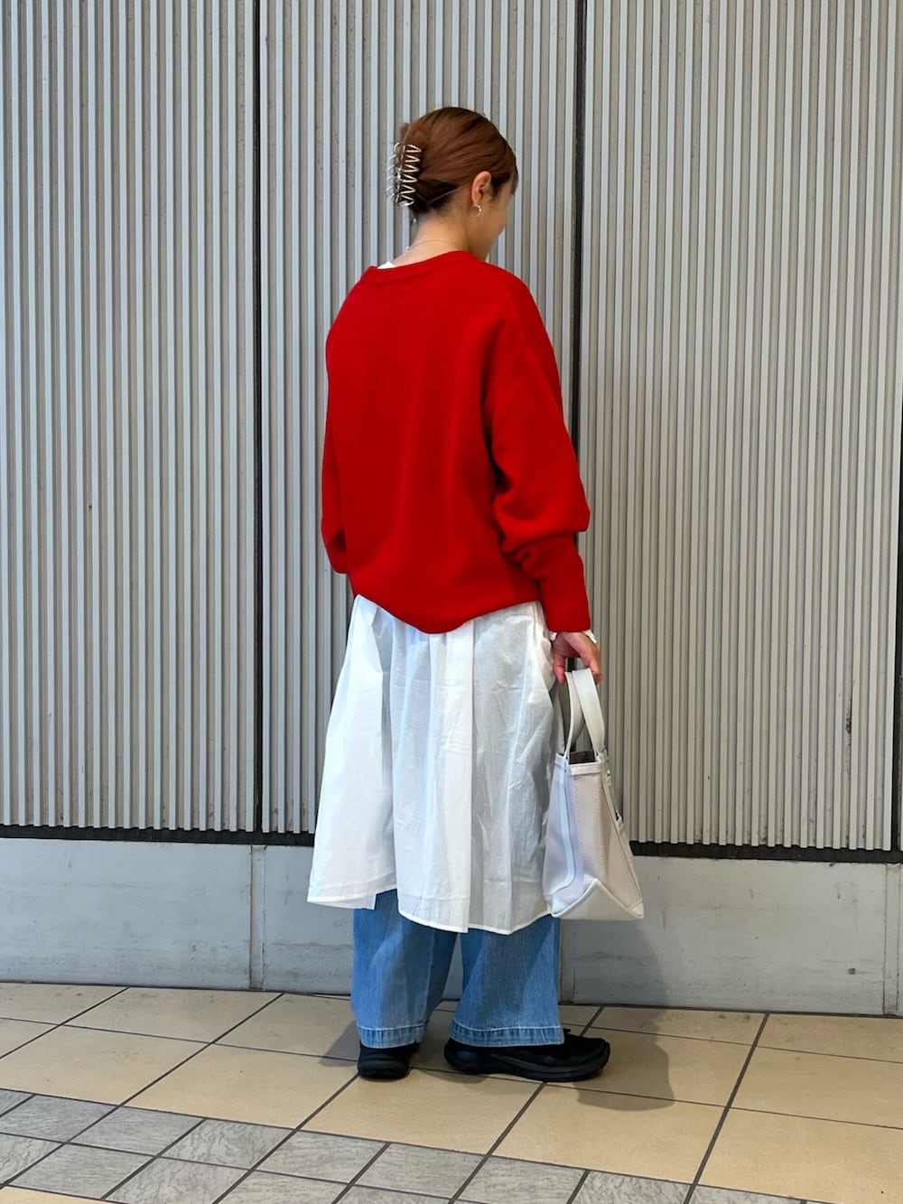 レッド系のニット/セーター、ブルー系のデニムパンツ、グレー系のトートバッグを着用したレディースの冬コーディネートの2枚目の写真