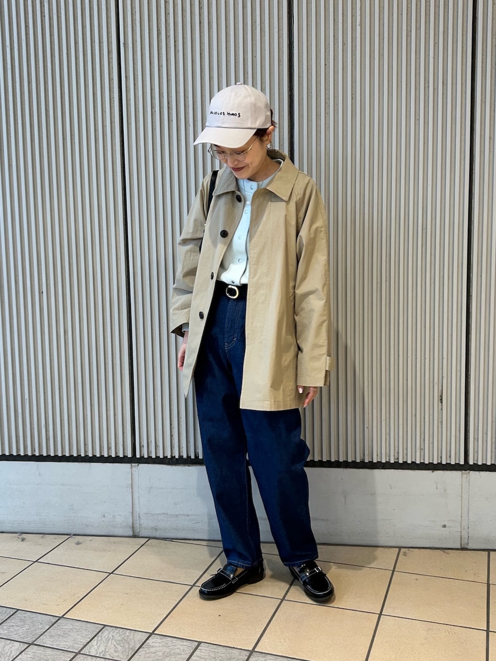 ベージュ系のステンカラーコート、グリーン系のカーディガン/ボレロ、ブラック系のローファーを着用したレディースの冬コーディネートの2枚目の写真