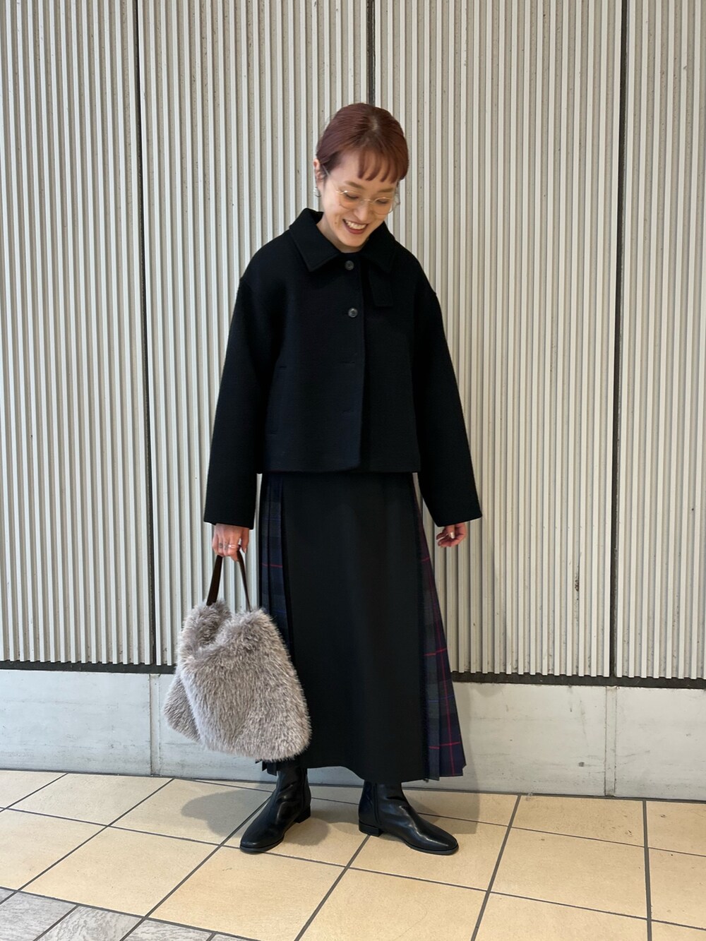 ブルー系のスカート、パープル系のニット/セーター、ブラック系のその他アウターを着用したレディースの秋コーディネートの4枚目の写真