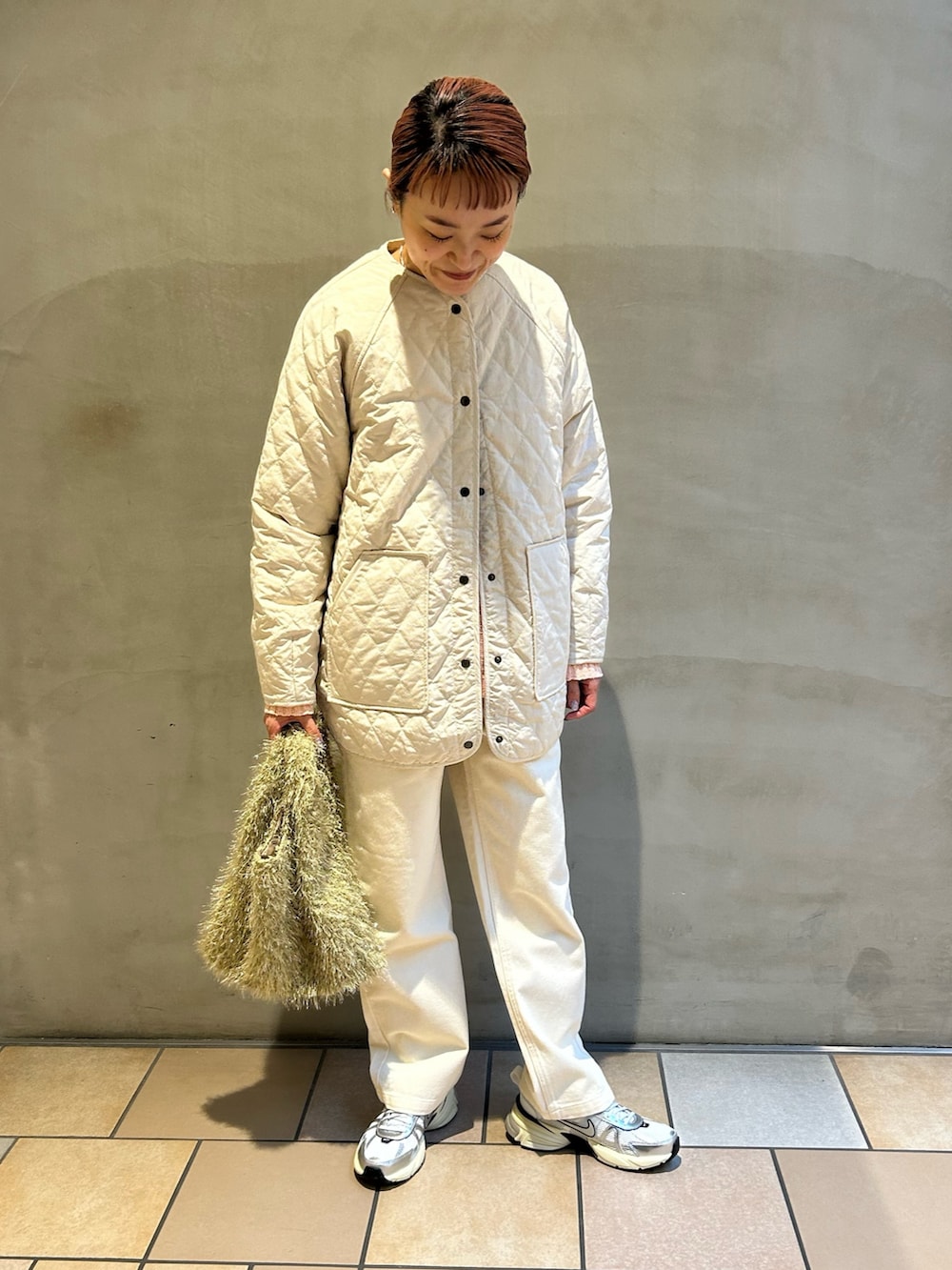 ピンク系のニット/セーター、ホワイト系のダウンジャケット/コート、ベージュ系のトートバッグを着用したレディースの冬コーディネートの5枚目の写真