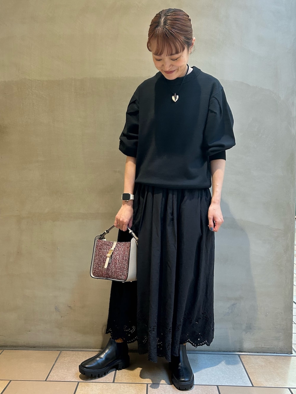 ブラック系のニット/セーター、ブラック系のスカート、レッド系のショルダーバッグを着用したレディースの秋コーディネートの6枚目の写真