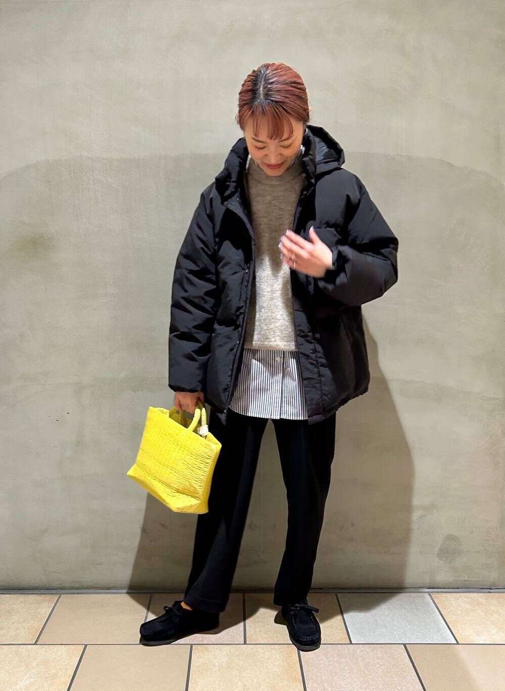 ブルー系のシャツ/ブラウス、イエロー系のトートバッグ、ブラック系のダウンジャケット/コートを着用したレディースの冬コーディネートの4枚目の写真