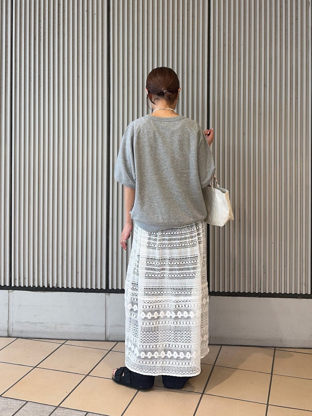 グレー系のシャツ/ブラウス、ホワイト系のショルダーバッグ、ブラック系のサンダルを着用したレディースの夏コーディネートの2枚目の写真
