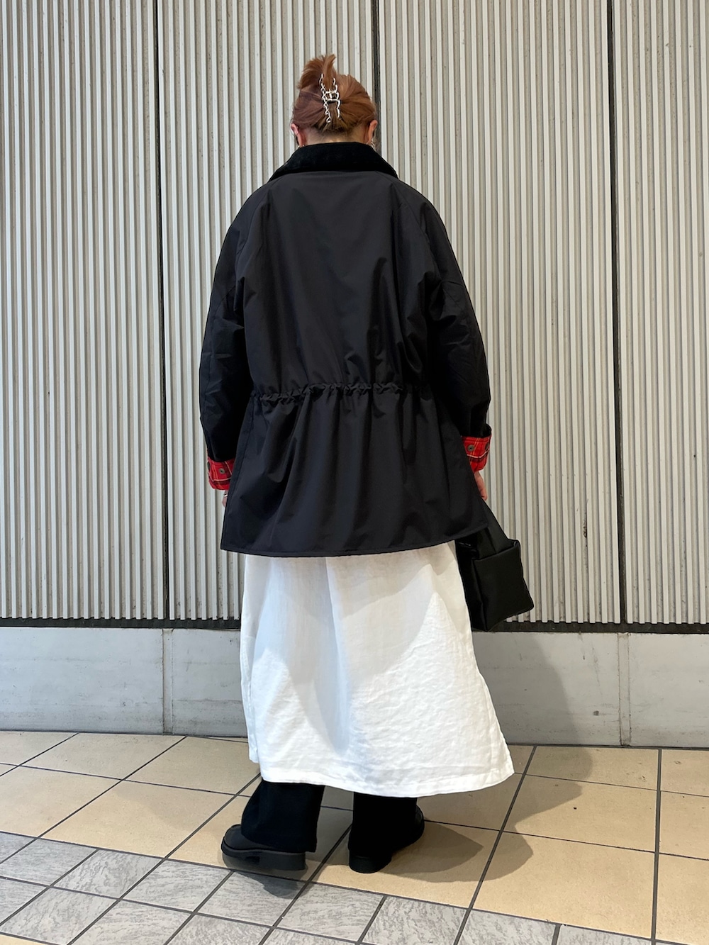 グレー系のベスト、ホワイト系のワンピース、ブラック系のその他パンツを着用したレディースの秋コーディネートの3枚目の写真