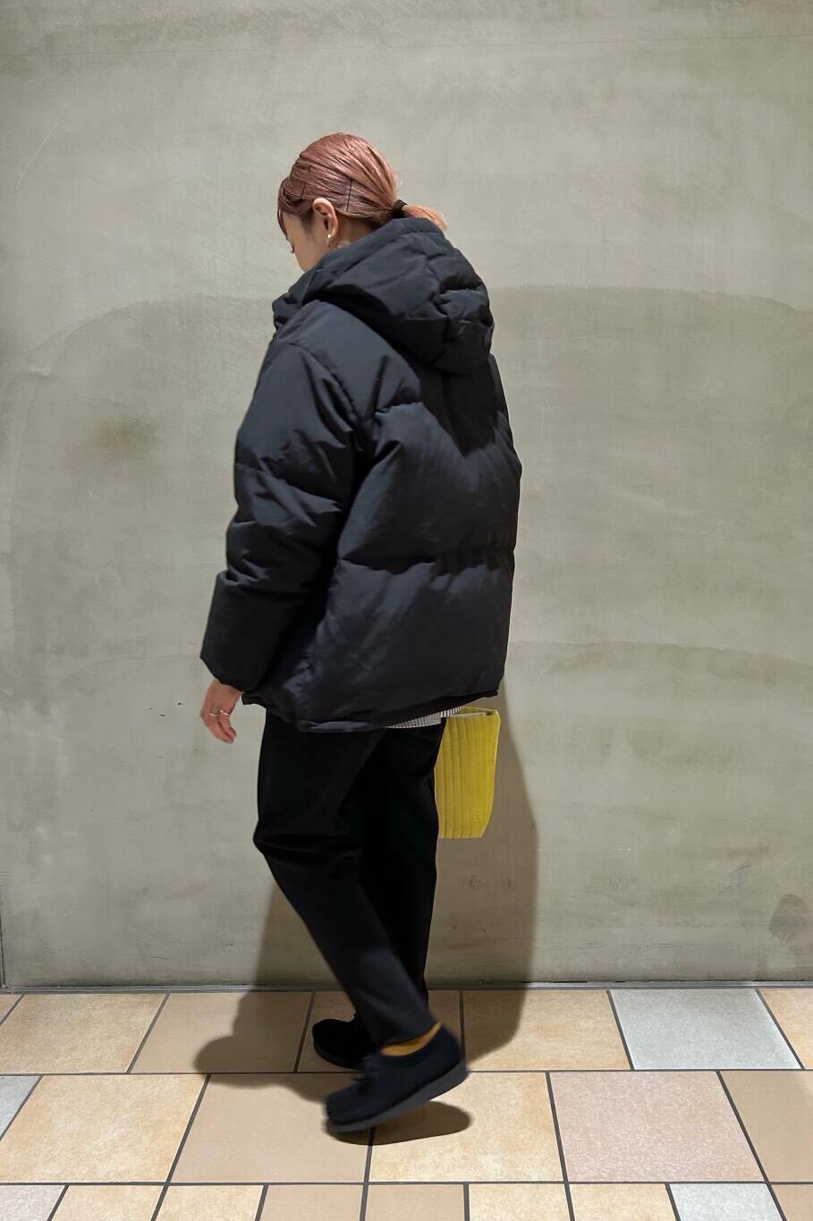 ブルー系のシャツ/ブラウス、イエロー系のトートバッグ、ブラック系のダウンジャケット/コートを着用したレディースの冬コーディネートの2枚目の写真