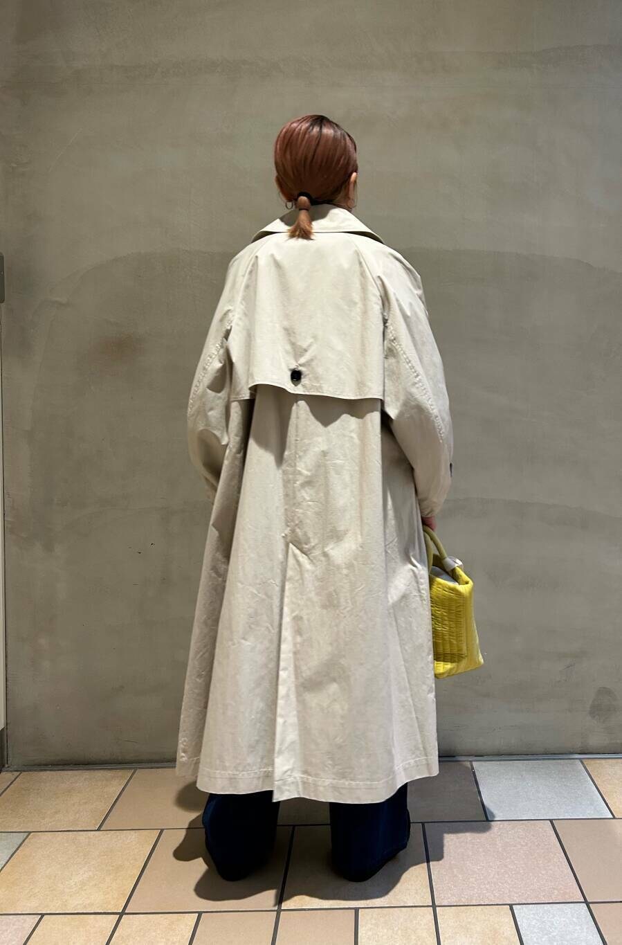 ブラック系のブーツ、イエロー系のトートバッグ、ブルー系のデニムパンツを着用したレディースの冬コーディネートの2枚目の写真