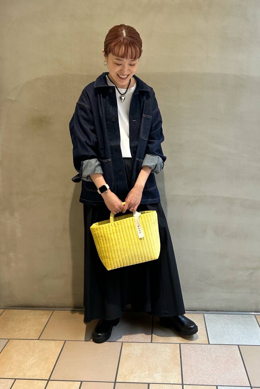 イエロー系のトートバッグ、ホワイト系のTシャツ/カットソー、ブラック系のブーツを着用したレディースの秋コーディネートの3枚目の写真