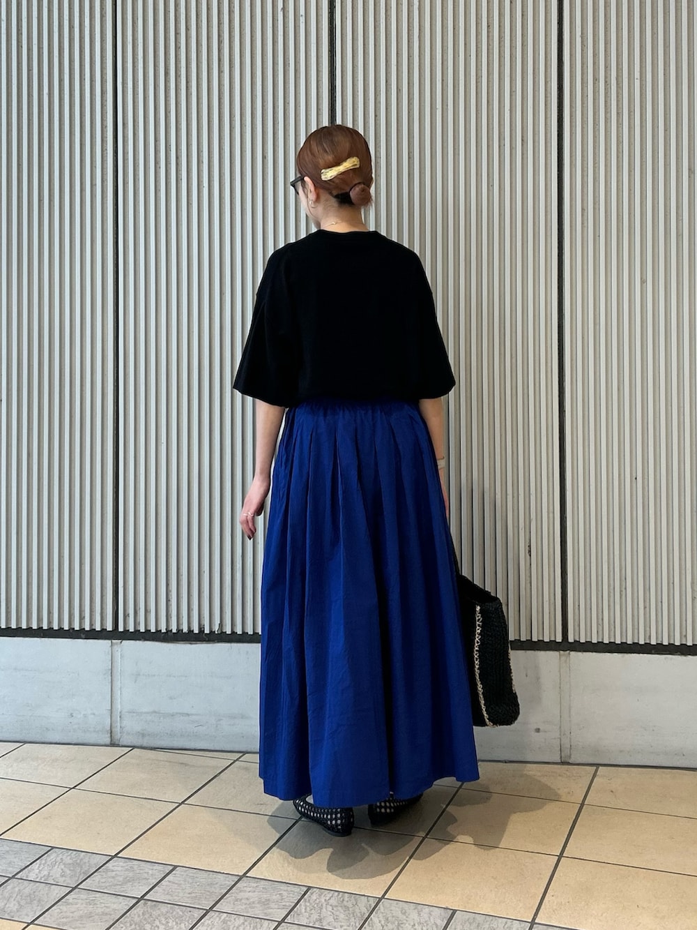 ブラック系のTシャツ/カットソー、ブルー系のスカート、ブラック系のサンダルを着用したレディースの夏コーディネートの2枚目の写真