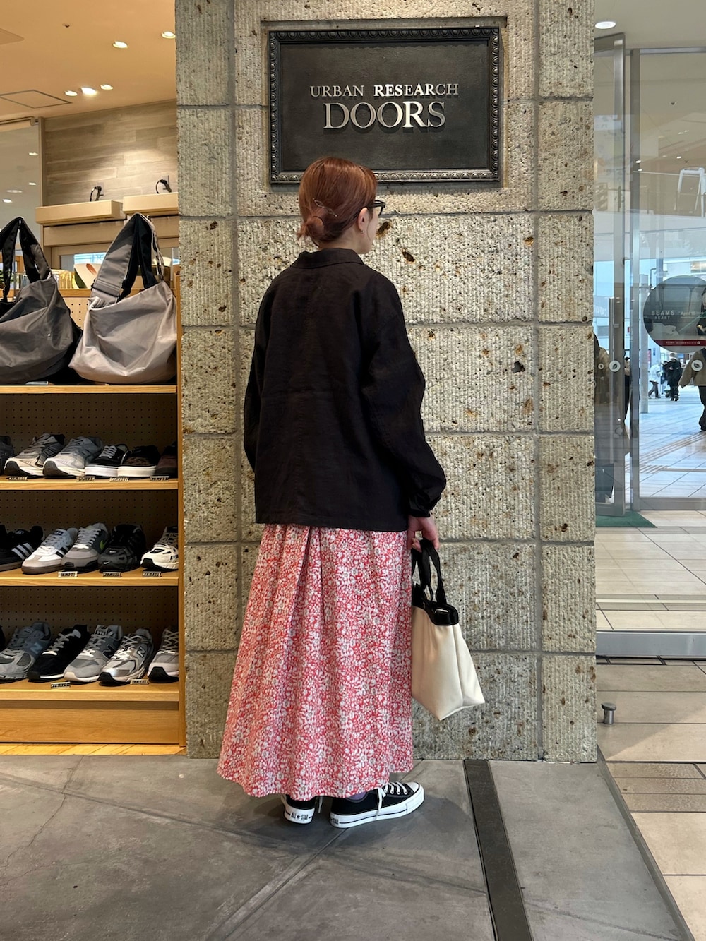 レッド系のスカート、ブラック系のスニーカー、ホワイト系のハンドバッグを着用したレディースの春コーディネートの3枚目の写真