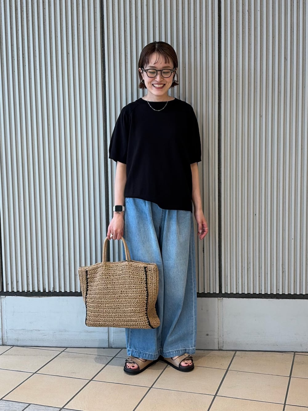 ブラック系のニット/セーター、ブルー系のデニムパンツ、ベージュ系のサンダルを着用したレディースの夏コーディネートの3枚目の写真