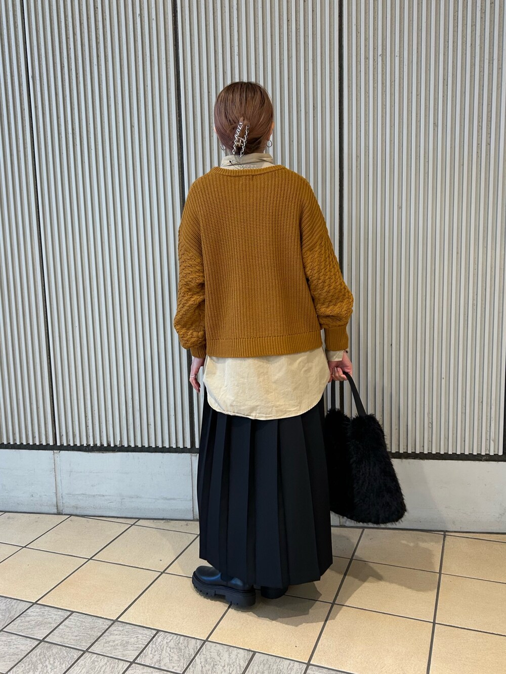 ゴールド系のニット/セーター、パープル系のシャツ/ブラウス、ブラック系のスカートを着用したレディースの冬コーディネートの2枚目の写真