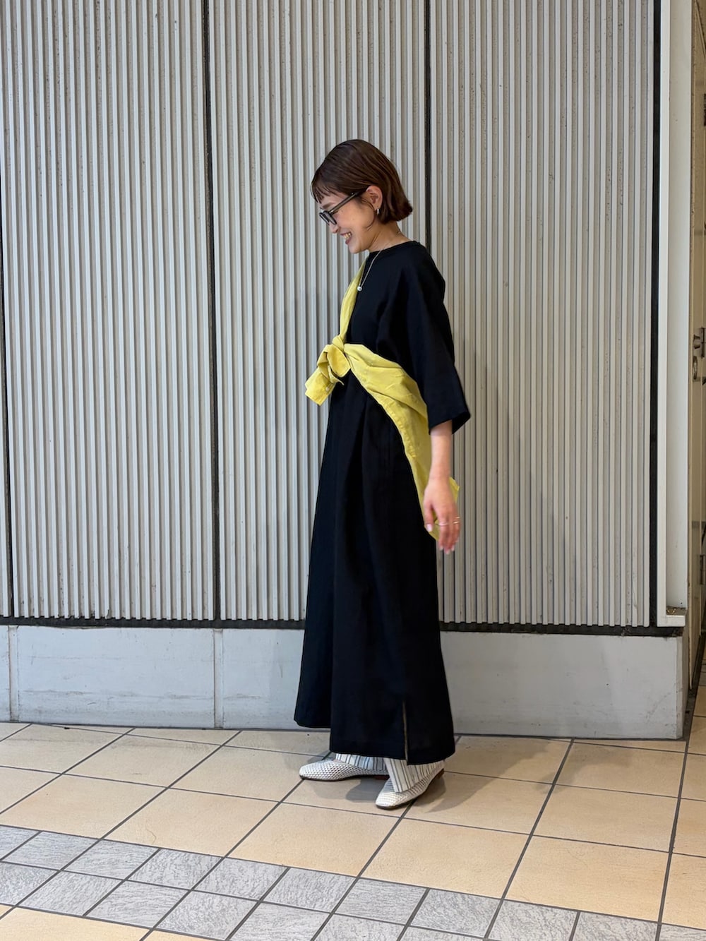 ブラック系のワンピース、イエロー系のシャツ/ブラウス、ベージュ系のその他パンツを着用したレディースの夏コーディネートの2枚目の写真