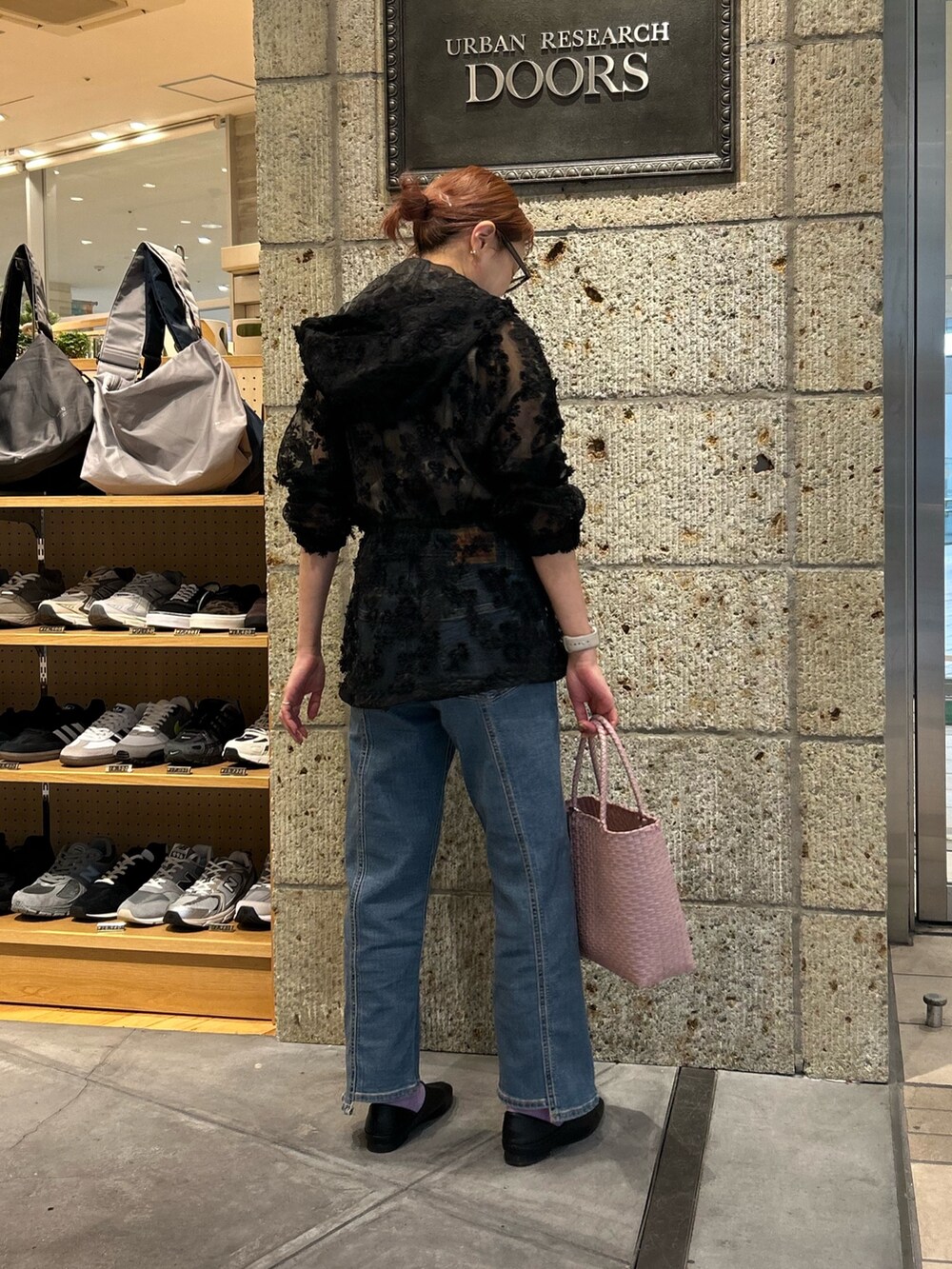 ブラック系のパーカー、ブルー系のデニムパンツ、ピンク系のハンドバッグを着用したレディースの春コーディネートの3枚目の写真