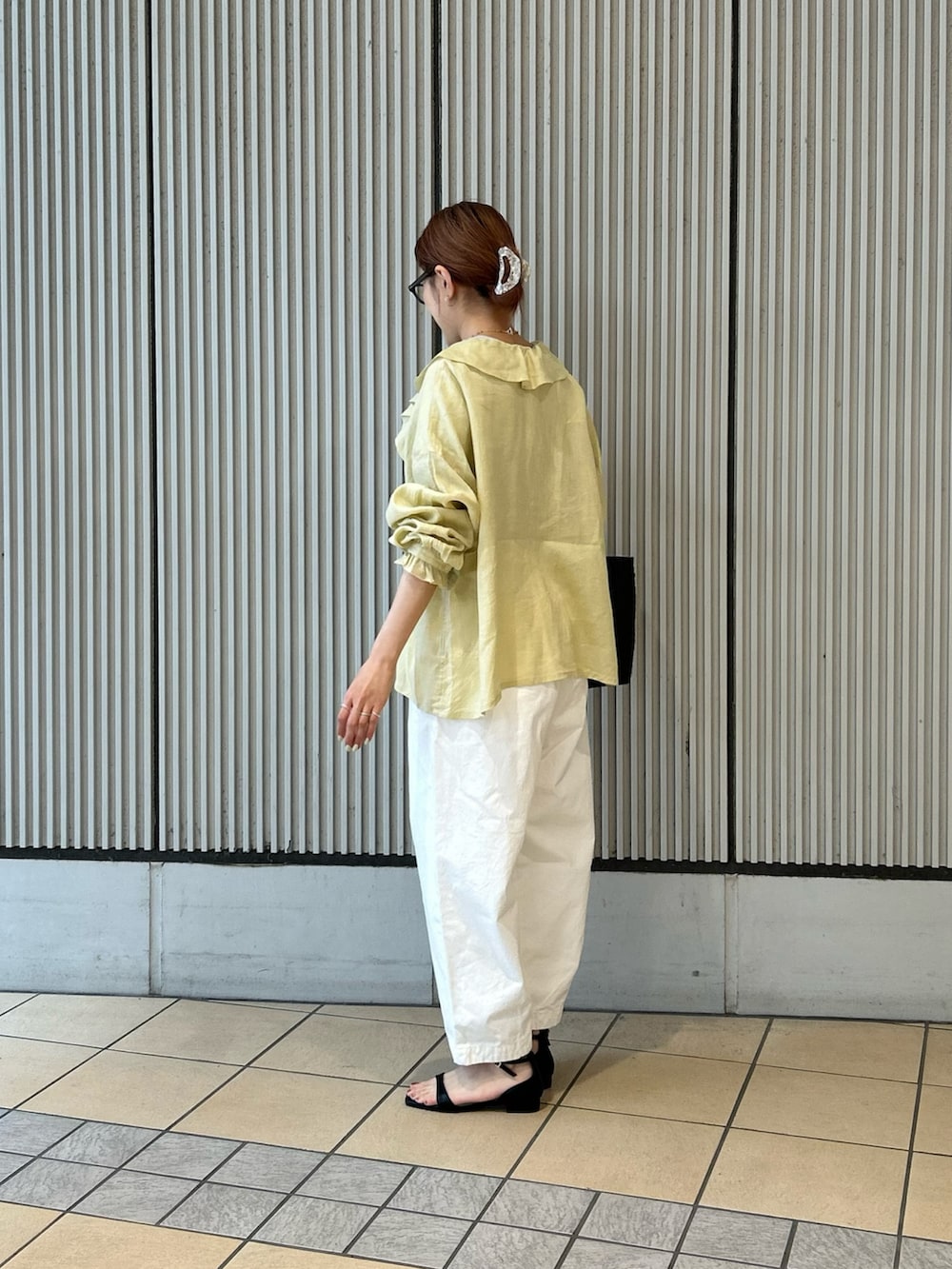 イエロー系のシャツ/ブラウス、ホワイト系のその他パンツ、ブラック系のサンダルを着用したレディースの春コーディネートの2枚目の写真