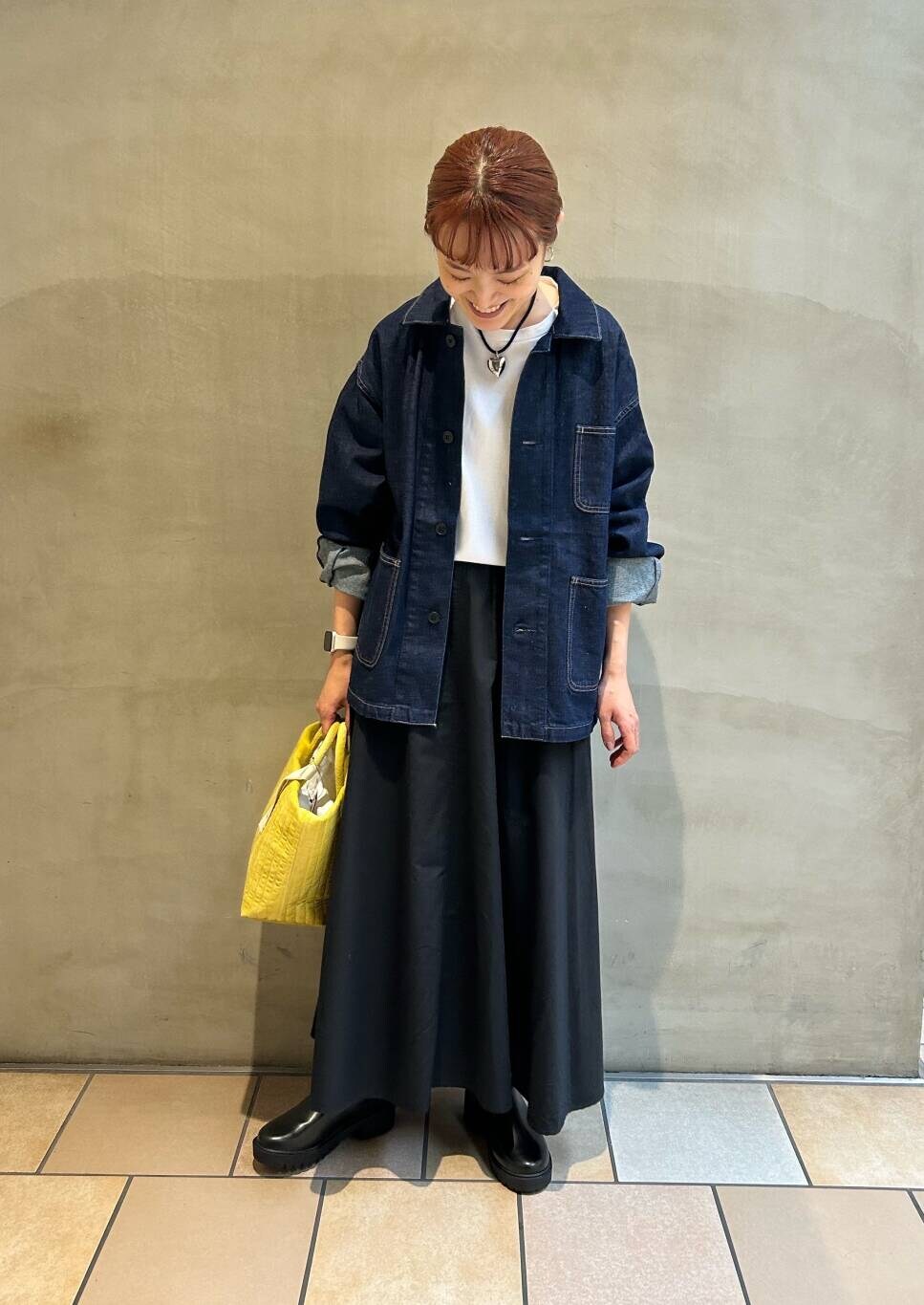 イエロー系のトートバッグ、ホワイト系のTシャツ/カットソー、ブラック系のブーツを着用したレディースの秋コーディネートの6枚目の写真