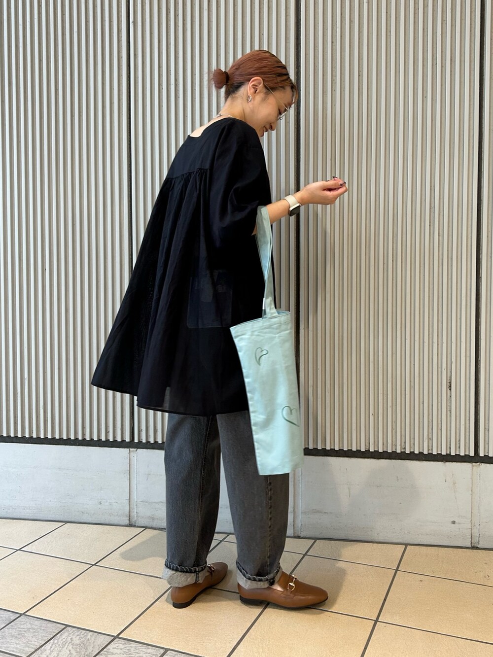 ブラック系のチュニック、ブラック系のデニムパンツを着用したレディースの夏コーディネートの3枚目の写真