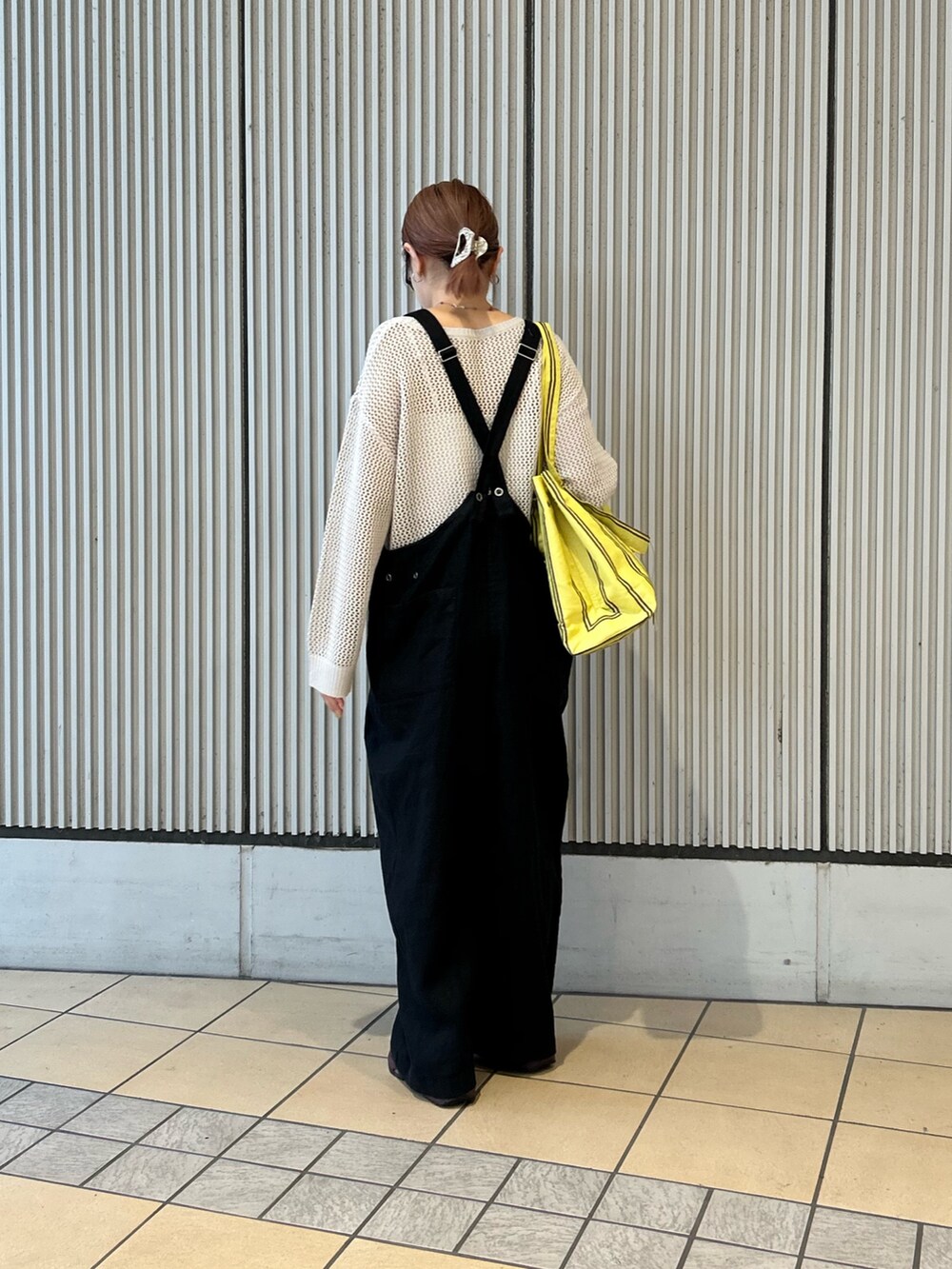 グレー系のニット/セーター、イエロー系のトートバッグ、レッド系のネックレスを着用したレディースの春コーディネートの2枚目の写真