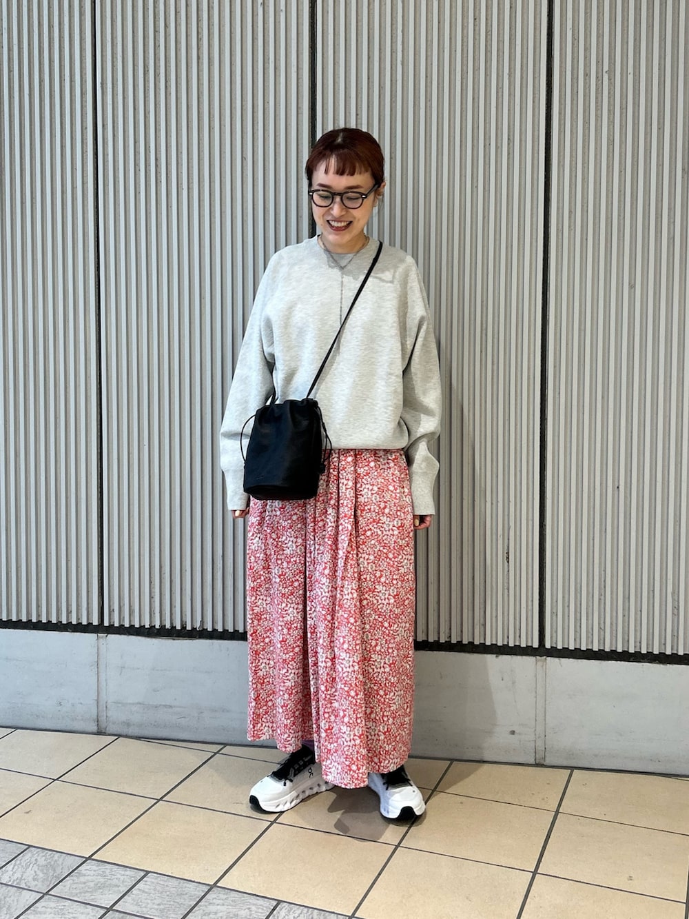 レッド系のスカート、グレー系のニット/セーター、ブラック系のスニーカーを着用したレディースの春コーディネートの4枚目の写真