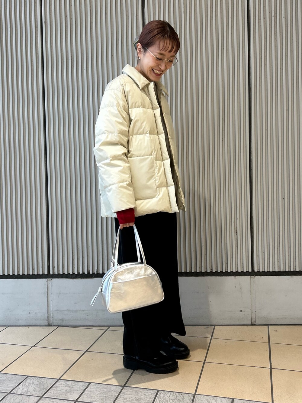 ホワイト系のダウンジャケット/コート、シルバー系のボストンバッグ、グレー系のニット/セーターを着用したレディースの秋コーディネートの2枚目の写真