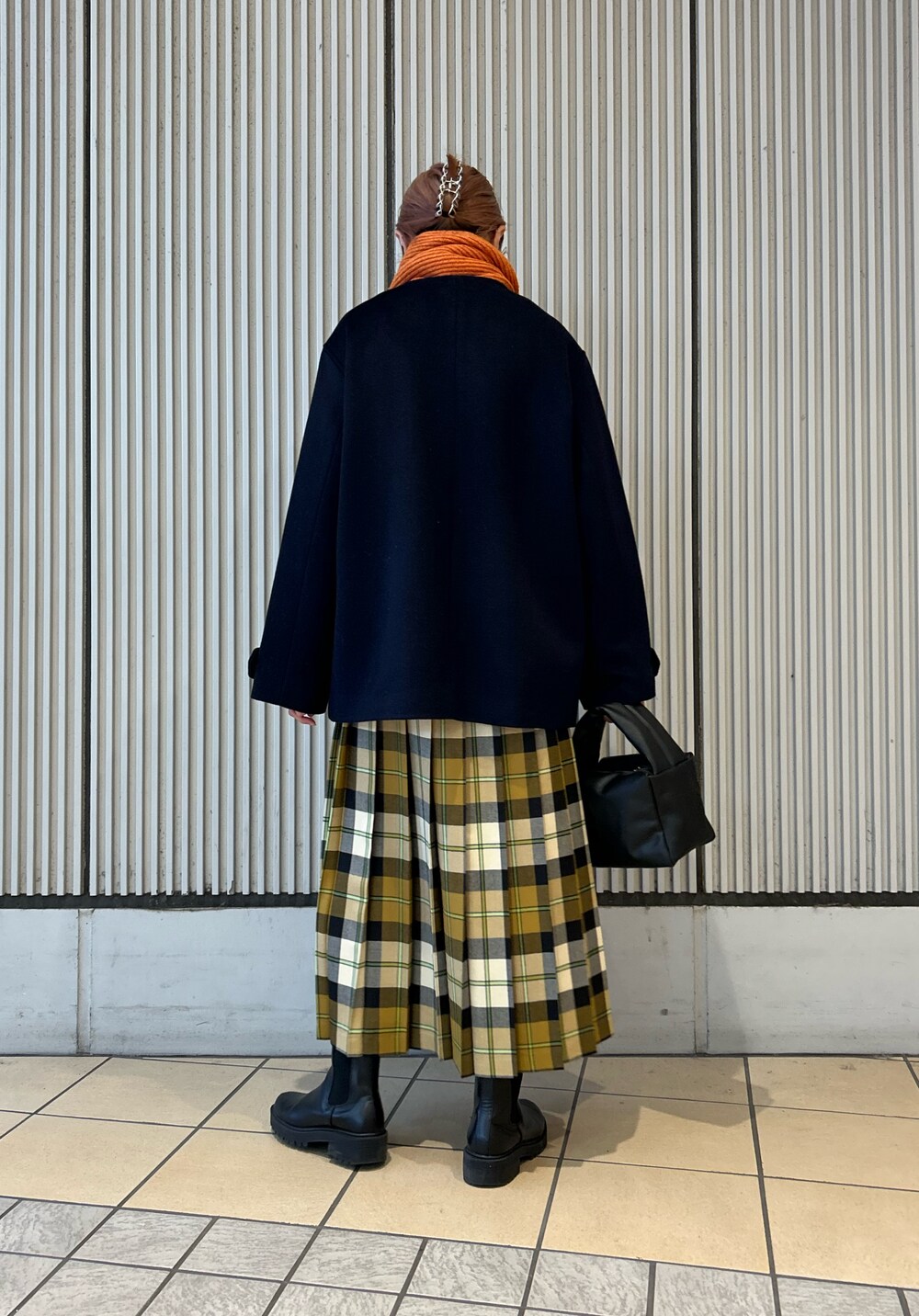 オレンジ系のニット/セーター、ベージュ系のスカート、ブラック系のハンドバッグを着用したレディースの冬コーディネートの6枚目の写真