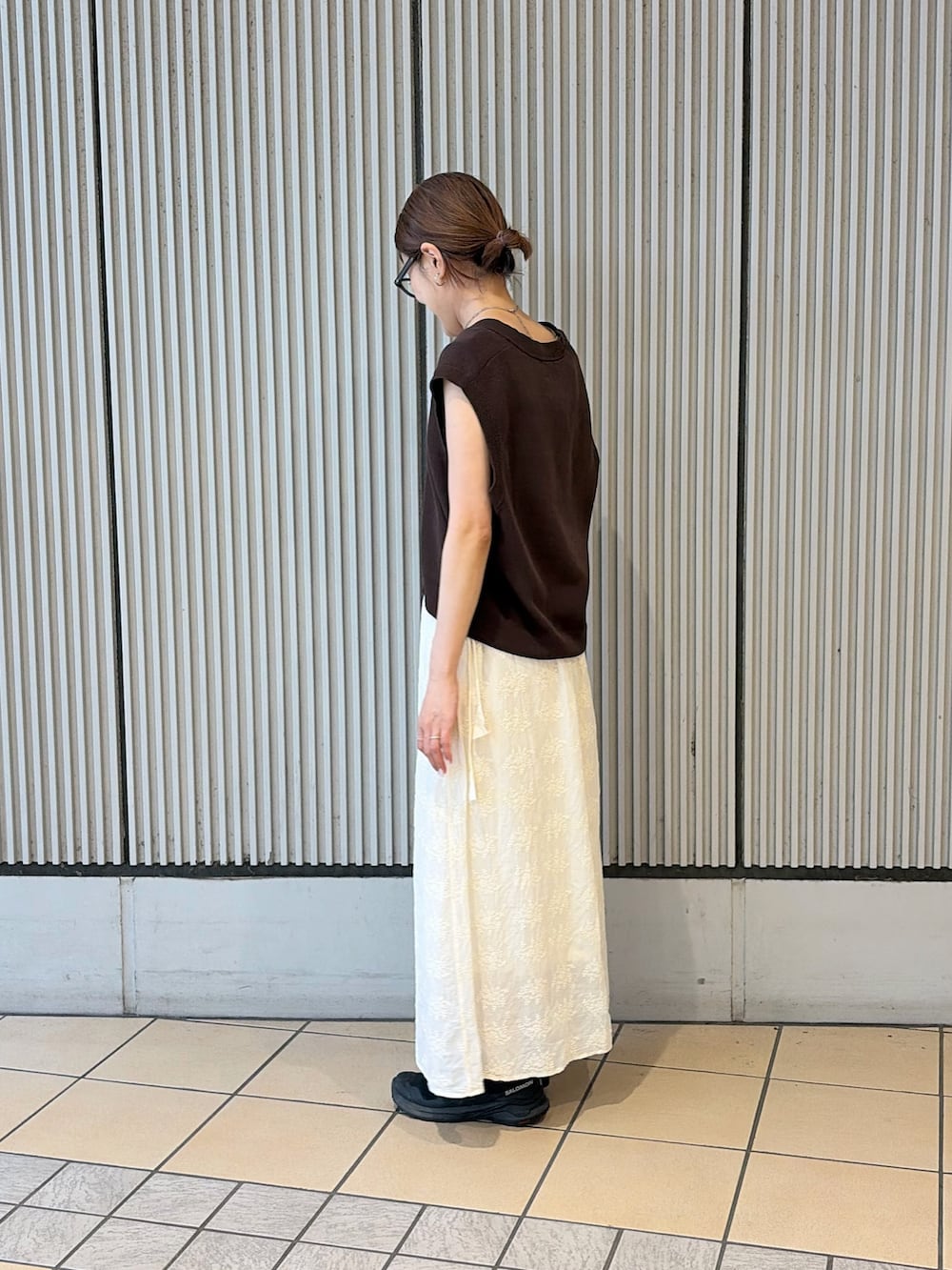 ブラウン系のベスト、ホワイト系のタンクトップ、ホワイト系のスカートを着用したレディースの夏コーディネートの2枚目の写真