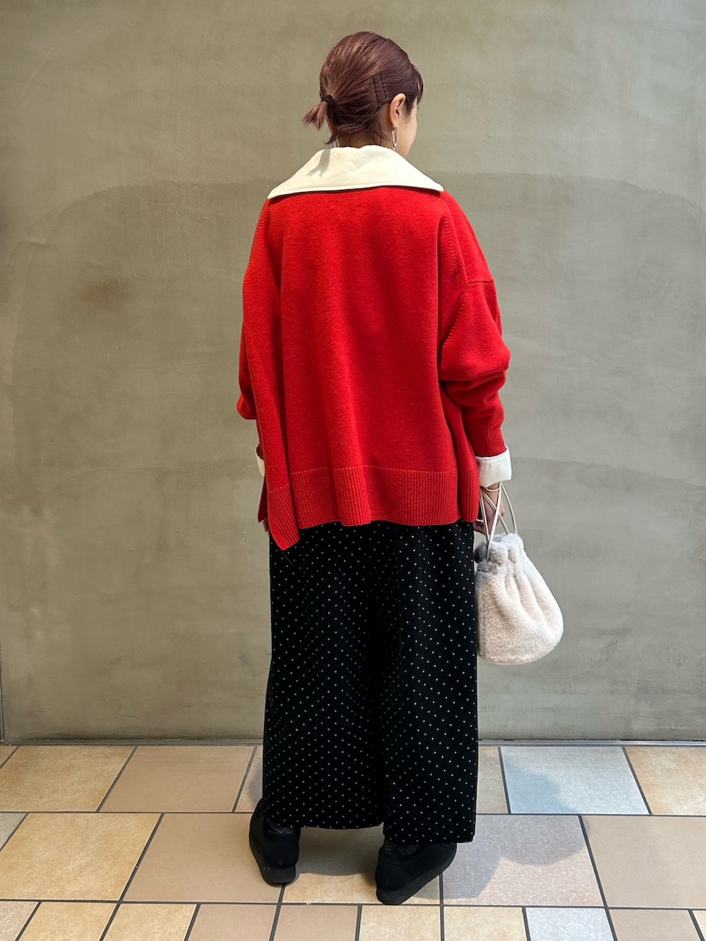 レッド系のニット/セーター、ブラック系のその他パンツ、ホワイト系のその他トップスを着用したレディースの冬コーディネートの3枚目の写真