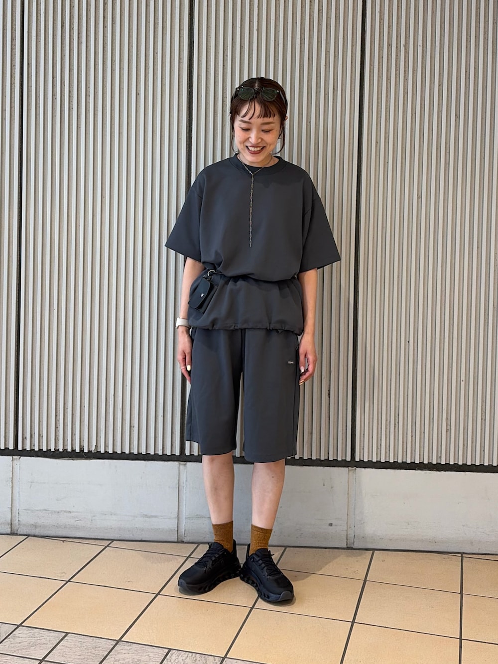 ブラック系のスニーカー、グレー系のルームウェア/パジャマ、ブラック系のポーチを着用したレディースの夏コーディネートの4枚目の写真