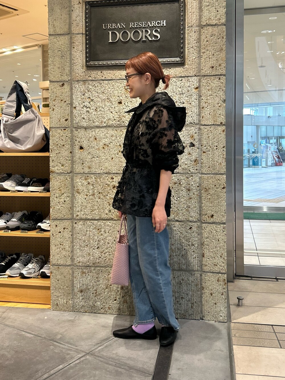 ブラック系のパーカー、ブルー系のデニムパンツ、ピンク系のハンドバッグを着用したレディースの春コーディネートの2枚目の写真