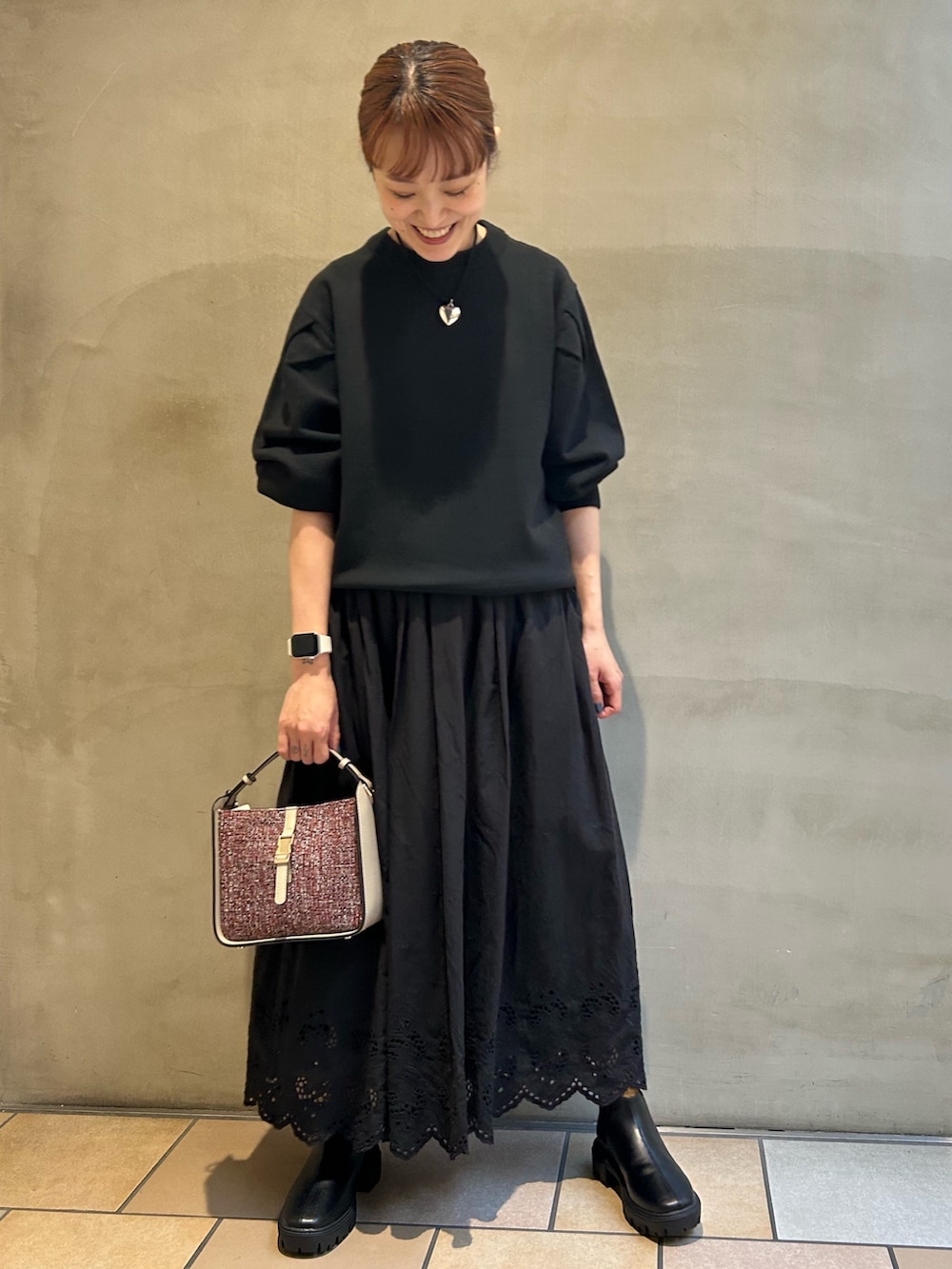 ブラック系のニット/セーター、ブラック系のスカート、レッド系のショルダーバッグを着用したレディースの秋コーディネートの2枚目の写真