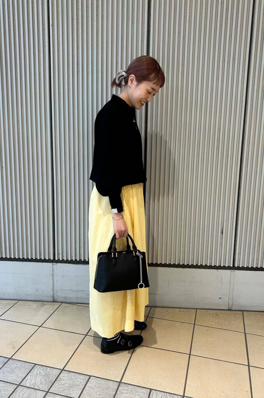 ブラック系のハンドバッグ、イエロー系のスカート、ブラック系のニット/セーターを着用したレディースの春コーディネートの3枚目の写真