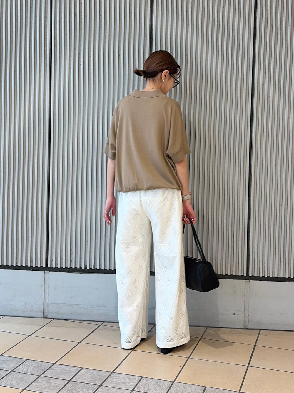 ベージュ系のニット/セーター、ホワイト系のその他パンツ、ブラック系のサンダルを着用したレディースの夏コーディネートの2枚目の写真