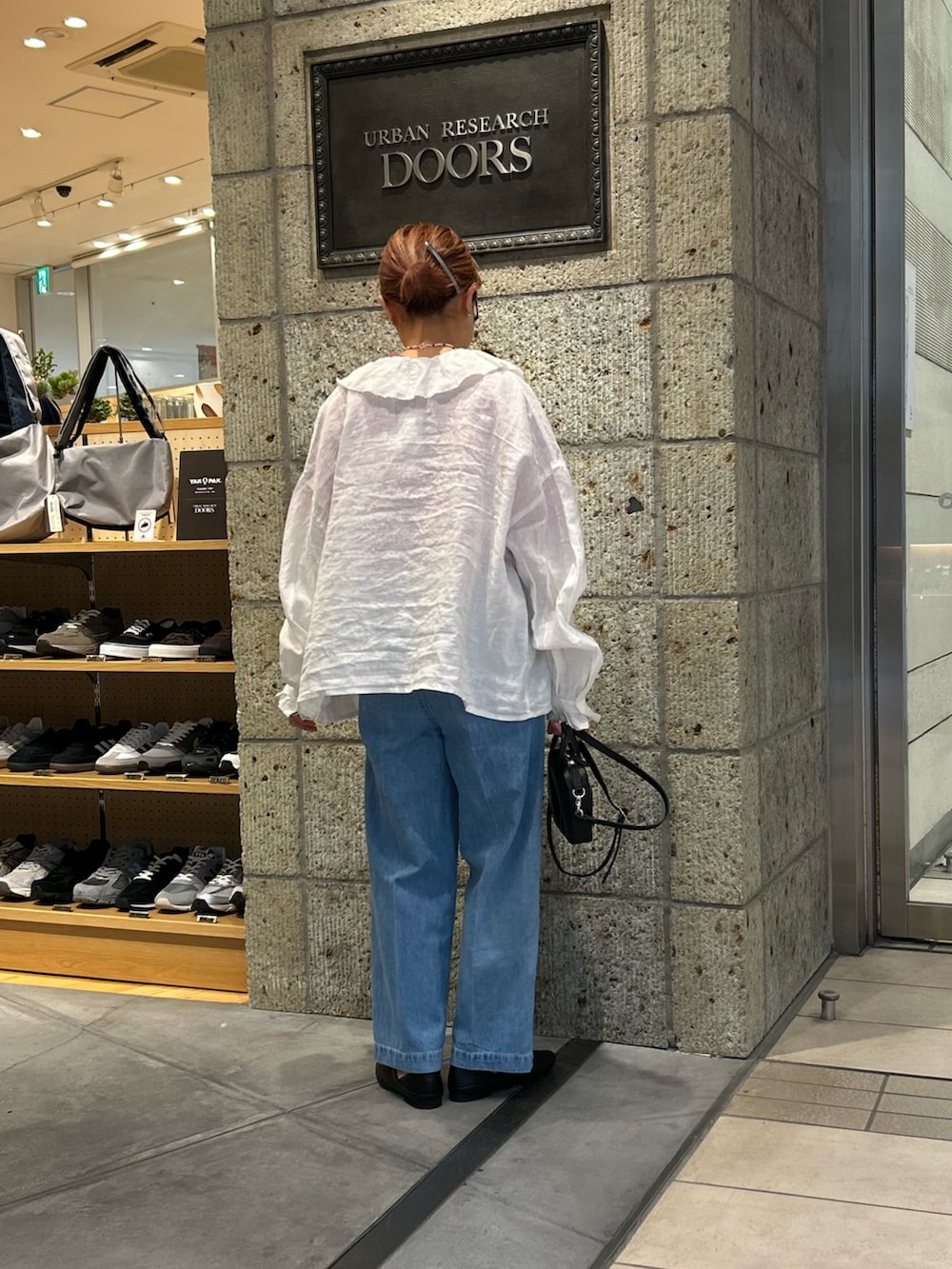 ブラック系のその他シューズ、ブルー系のデニムパンツ、ブラック系のショルダーバッグを着用したレディースの春コーディネートの2枚目の写真