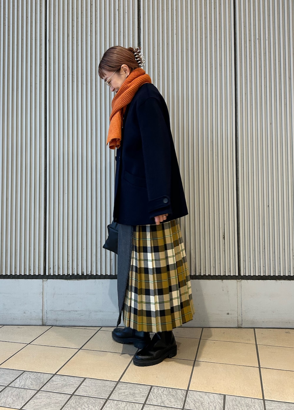 オレンジ系のニット/セーター、ベージュ系のスカート、ブラック系のハンドバッグを着用したレディースの冬コーディネートの5枚目の写真