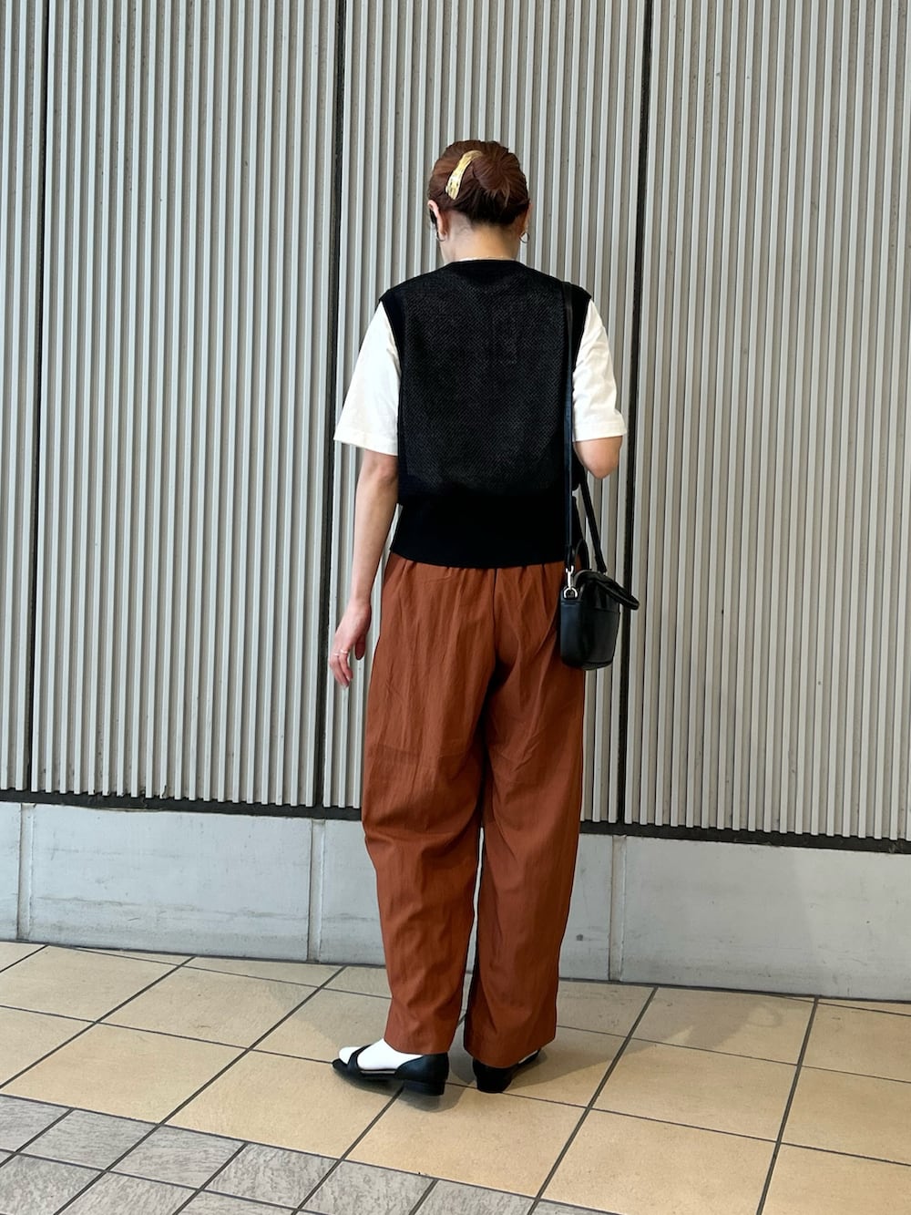 オレンジ系のその他パンツ、ブラック系のベスト、ブラック系のショルダーバッグを着用したレディースの春コーディネートの3枚目の写真