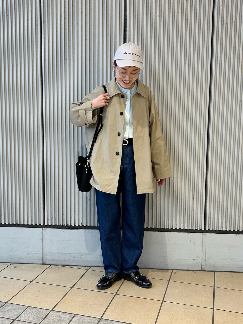 ベージュ系のステンカラーコート、グリーン系のカーディガン/ボレロ、ブラック系のローファーを着用したレディースの冬コーディネートの4枚目の写真