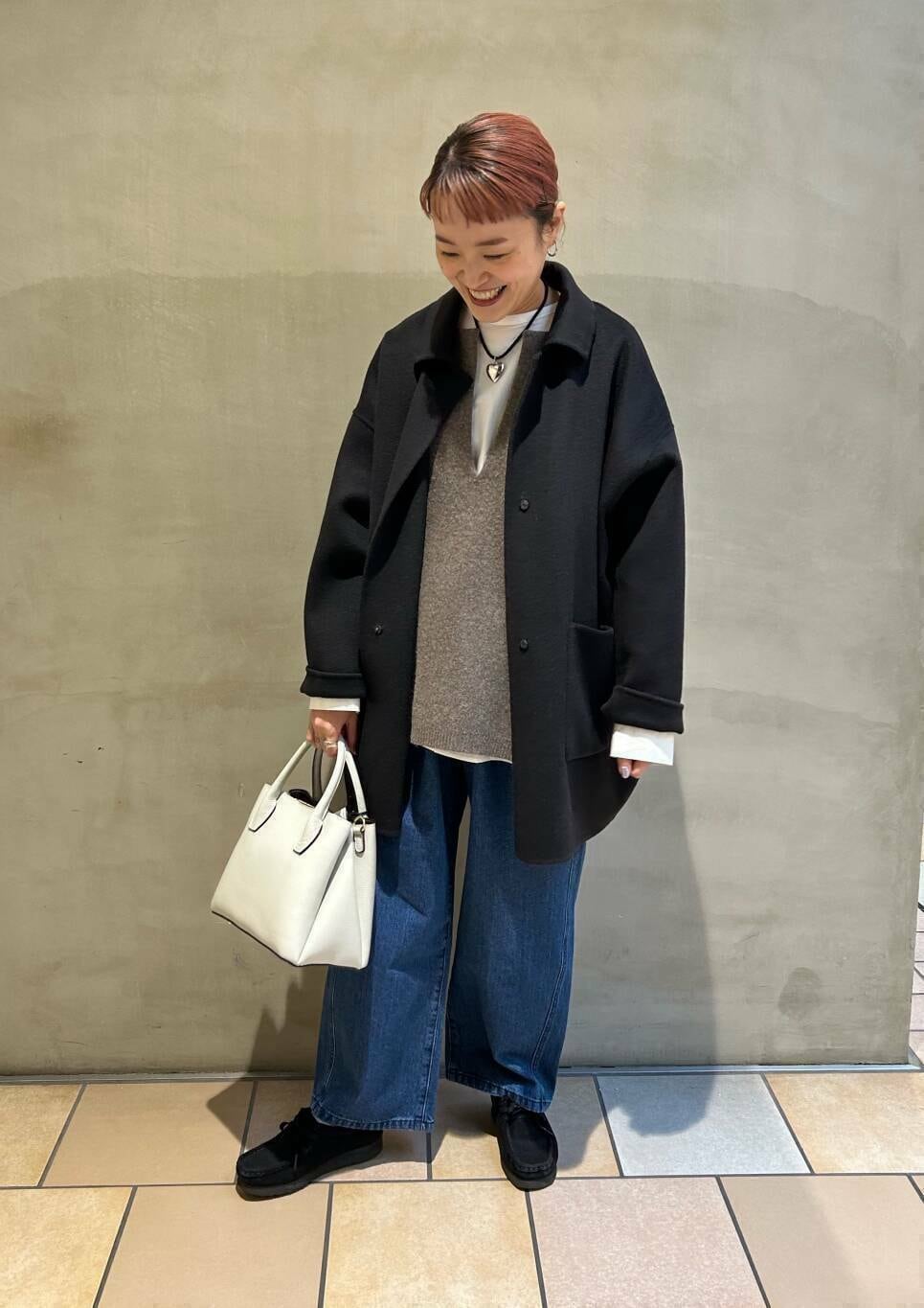 ブラック系のブーツ、ホワイト系のショルダーバッグ、ブルー系のデニムパンツを着用したレディースの冬コーディネートの6枚目の写真