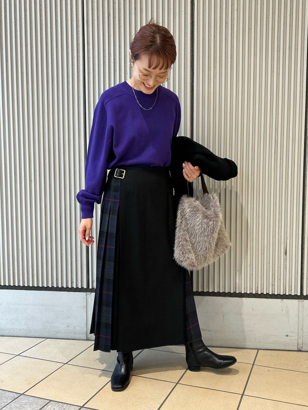 ブルー系のスカート、パープル系のニット/セーター、ブラック系のその他アウターを着用したレディースの秋コーディネートの3枚目の写真