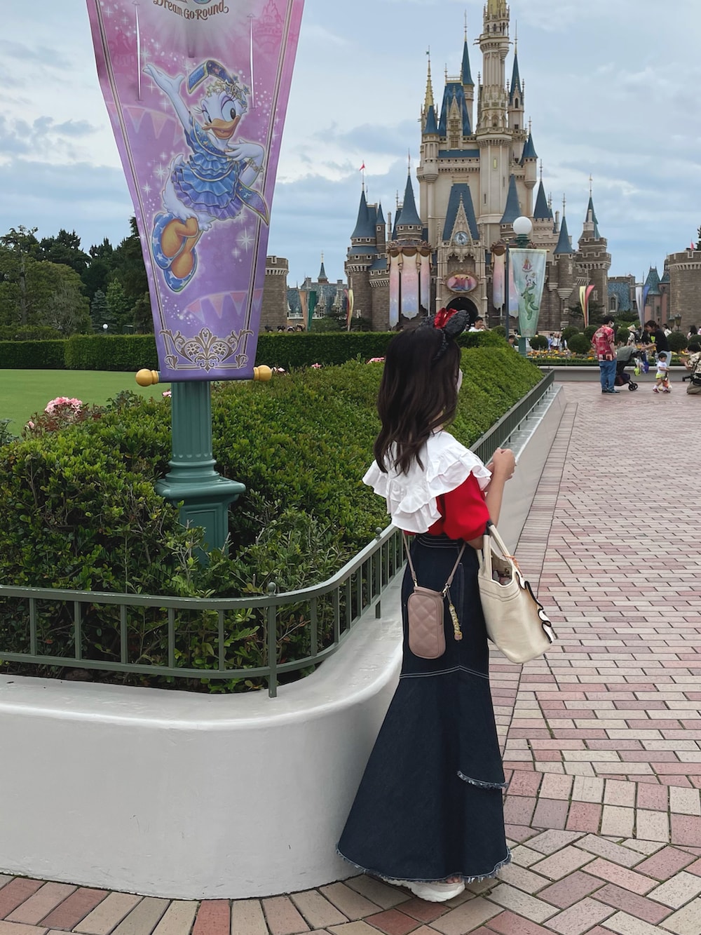 レッド系のスウェット、ホワイト系のトートバッグ、ブルー系のデニムスカートを着用したレディースの春コーディネートの3枚目の写真