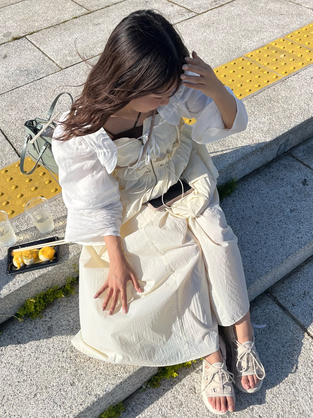 グリーン系のバッグ、ベージュ系のサンダル、ベージュ系のワンピースを着用したレディースの春コーディネートの3枚目の写真