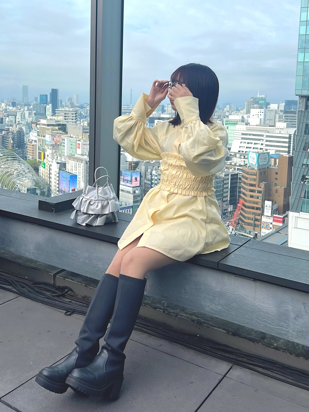 ブラック系のデニムジャケット、イエロー系のシャツ/ブラウス、シルバー系のショルダーバッグを着用したレディースの春コーディネートの2枚目の写真