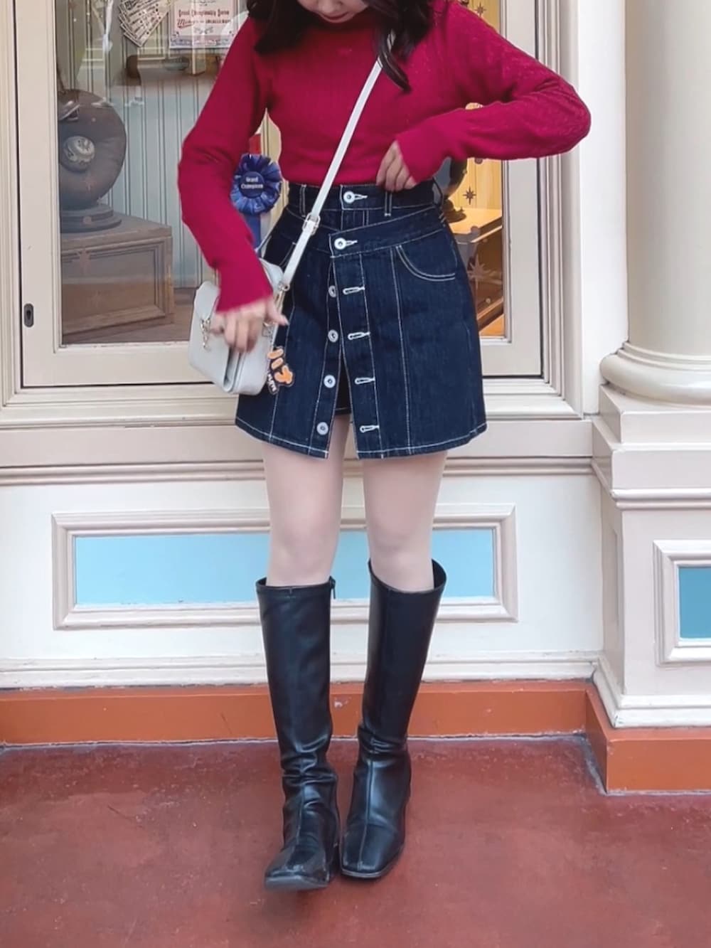 レッド系のニット/セーター、ブラック系のスカート、ブラック系のブーツを着用したレディースの春コーディネートの3枚目の写真