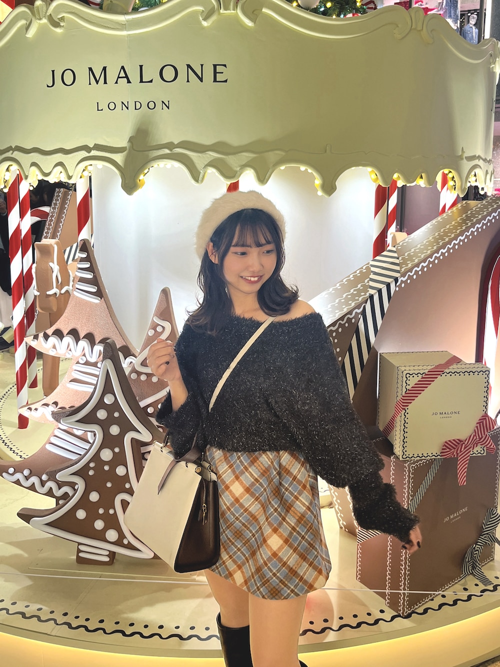 ブラック系のニット/セーター、ブルー系のスカート、ブラック系のブーツを着用したレディースの春コーディネートの3枚目の写真