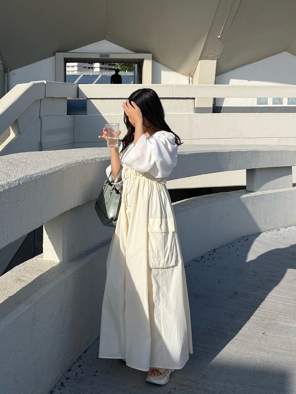 グリーン系のバッグ、ベージュ系のサンダル、ベージュ系のワンピースを着用したレディースの春コーディネートの2枚目の写真